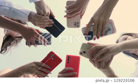 A diverse group of hands collectively holding and displaying various smartphones, showcasing modern connectivity 129228106