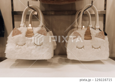 cute fluffy white unicorn bags on shelf in store trendy accessories for children. closeup. cute fluffy white unicorn bags on shelf in store trendy accessories for children. closeup. 129228715