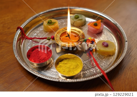 Raksha Bandhan Thali with Diya, Sweets, Kumkum, and Rakhi on Wooden Table 129229021