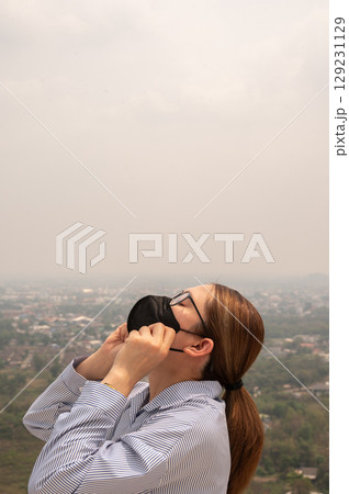 Asian businesswoman wearing N95 mask for protect Bad air pollution (PM2.5). PM2.5 levels meaning the air quality posed a health hazard. 129231129