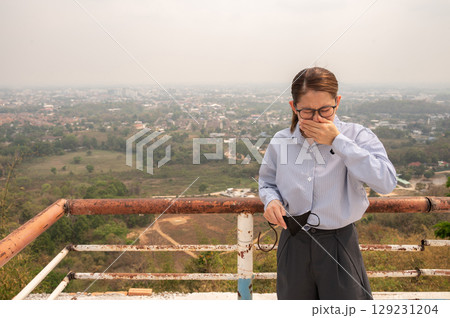 Asian businesswoman feel worrying about bad air pollution covered her hometown in Thailand. PM2.5 levels meaning the air quality posed a health hazard. 129231204