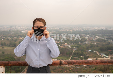 Asian businesswoman wearing N95 mask for protect Bad air pollution (PM2.5). PM2.5 levels meaning the air quality posed a health hazard. Asian businesswoman wearing N95 mask for protect Bad air pollution (PM2.5). PM2.5 levels meaning the air quality posed a health hazard. 129231236