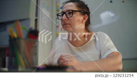 Primary School Teacher Working on Computer, Checking Homework and Online Tasks During E-Learning Primary School Teacher Working on Computer, Checking Homework and Online Tasks During E-Learning 129231254