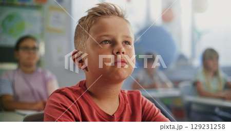 Close Up of Elementary School Boy Sitting at the Desk, Listening to Lecture from Teacher 129231258