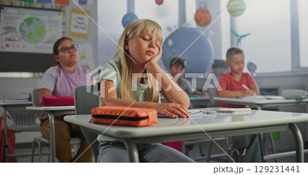 Sad Primary School Girl Sitting at Desk, Getting Tired During Lesson or Upset Because of Bad Grade 129231441