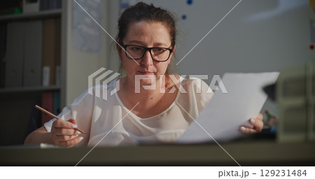 Female Teacher Grading Writing Tasks or Homework, Checking School Exam, Sitting at Desk 129231484