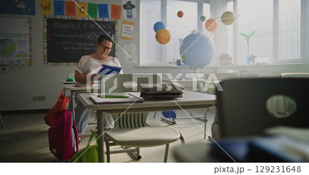 Exhausted Female Teacher Sitting Alone at Desk in Empty Classroom, Having Rest After Lesson 129231648