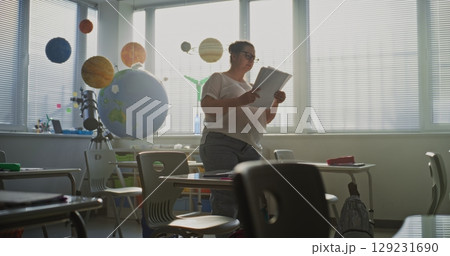 Female Teacher Organizing Space for School Exam in Classroom in Modern Primary School 129231690