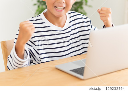 家でパソコンをしながらガッツポーズをする小学生の男の子 家でパソコンをしながらガッツポーズをする小学生の男の子 129232564