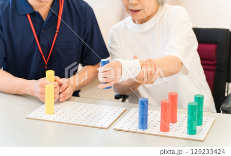 介護施設・リハビリ施設で働く作業療法士の職員とリハビリをするシニア女性 129233424