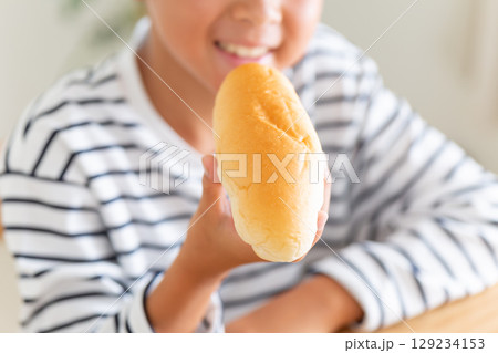 コッペパンを食べる小学生の男の子 129234153
