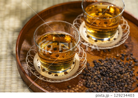 木のお盆に並ぶ麦茶のグラスと焙煎大麦 129234403