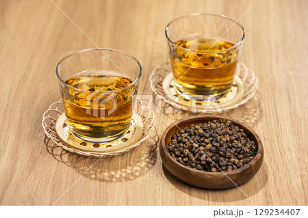 木のテーブルに並べた麦茶のグラスと焙煎大麦の粒 木のテーブルに並べた麦茶のグラスと焙煎大麦の粒 129234407