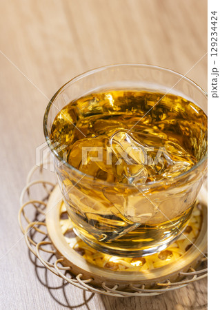 木目のテーブルに置かれた氷入り麦茶 129234424