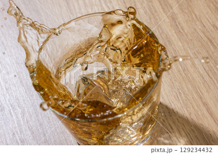 夏の冷たい麦茶に氷を入れる瞬間のしぶきが美しいドリンク 129234432