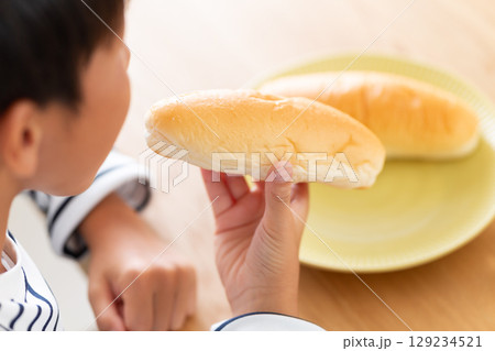 コッペパンを食べる小学生の男の子 129234521