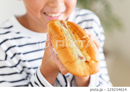 惣菜パンのホットドックを食べる小学生の男の子 129234624