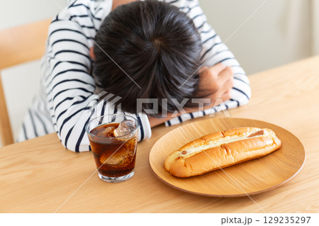 菓子パンを前に悩む小学生の男の子 129235297