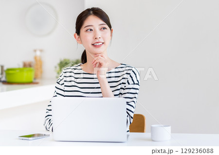 リビングでテレワークをする若い女性。 リビングでテレワークをする若い女性。 129236088