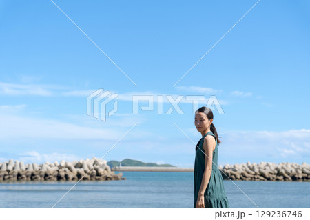 青い海に立つ若い女性 129236746