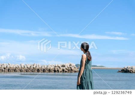 青い海に立つ若い女性 129236749