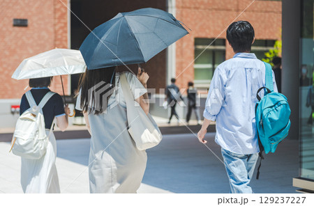 日傘をさして歩く男女学生グループの後ろ姿 日傘をさして歩く男女学生グループの後ろ姿 129237227