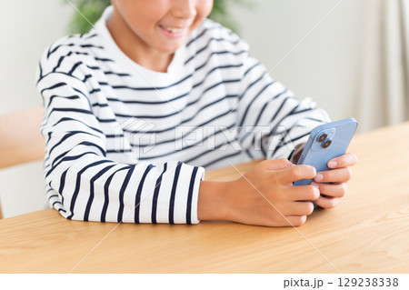 家でスマホを見る小学生の男の子 129238338