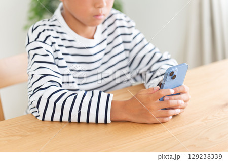家でスマホを見る小学生の男の子 129238339