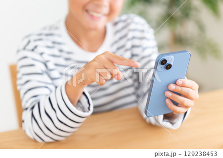 家でスマホを見る小学生の男の子 129238453