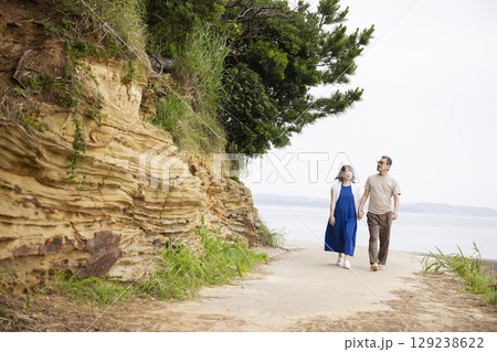 海岸沿いを歩く夫婦の後ろ姿 129238622