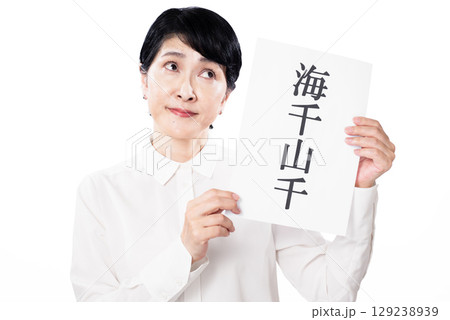 海千山千と書かれた紙を持ち考えている中年女性 海千山千と書かれた紙を持ち考えている中年女性 129238939