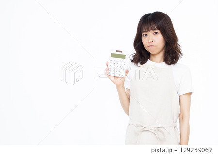電卓を持って真剣に悩んでいる主婦 129239067