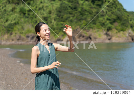 砂浜でシーグラスを拾う女性 129239094