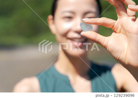 砂浜でシーグラスを拾う女性 129239096
