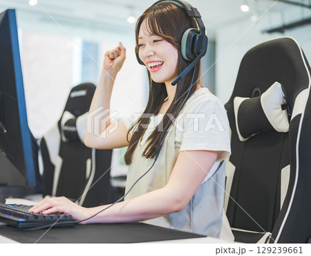 　ゲームでガッツポーズをする女子学生 129239661