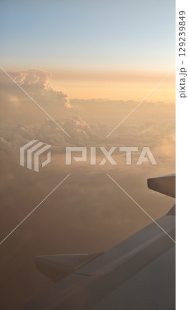 View from airplane window during golden sunset with fluffy clouds glowing in warm light 129239849