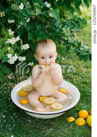 Baby Enjoying Orange Slice Sitting In Bowl Outdoors 129240667