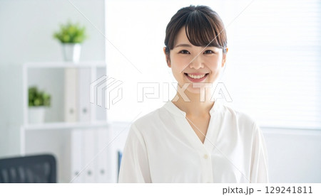 明るいオフィスで笑顔を見せる若い日本人女性ビジネスパーソンのポートレート 129241811