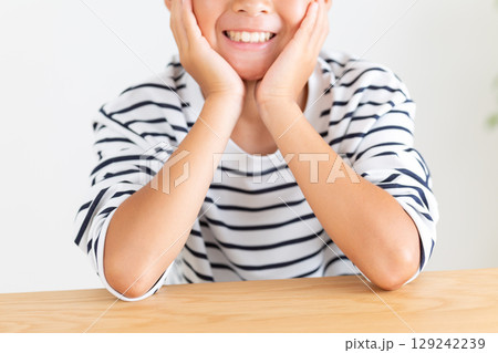 頬杖をついて微笑む小学生の男の子 129242239