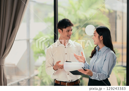 Asian coworkers exchanging thoughts and planning strategy in modern office 129243383