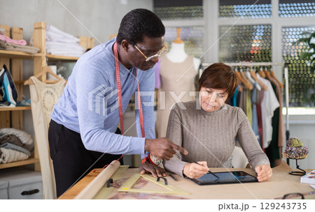 Woman and African American man tailor creates sketch of dress on tablet 129243735