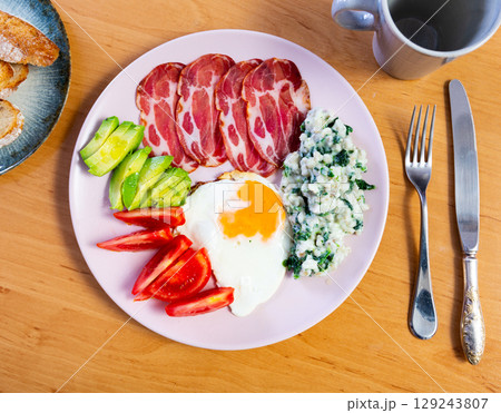 Breakfast plate containing fried egg, ham, tomato, avocado and porridge Breakfast plate containing fried egg, ham, tomato, avocado and porridge 129243807