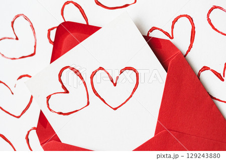Handmade Valentine's Day card with red printed heart stamps in red envelope on white background. 129243880