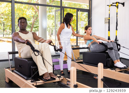 African american man doing pilates exercises lying on pilates workout machines closeup African american man doing pilates exercises lying on pilates workout machines closeup 129243939