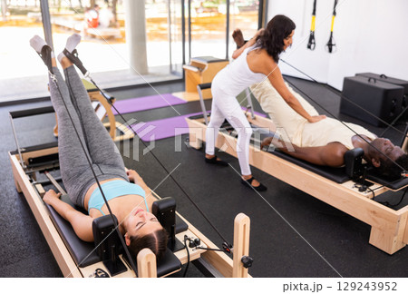 Multethnic group of people training pilates in gym with trainer 129243952