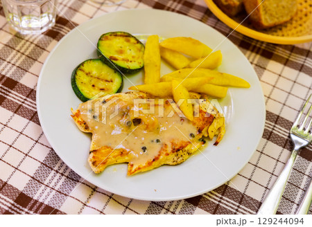 Tender meat of baked chicken breast with pepper garnished with French fries 129244094