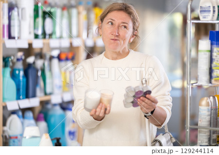 Female shopper chooses scented candles in supermarket for romantic evening 129244114