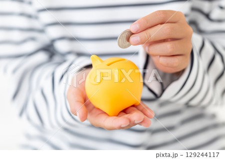 黄色の豚の貯金箱にお金を入れる小学生の男の子 黄色の豚の貯金箱にお金を入れる小学生の男の子 129244117
