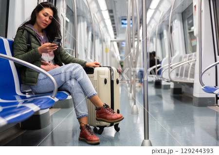 Woman passenger using phone in subway car 129244393