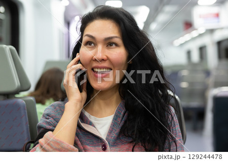 Woman traveler talking on mobile phone in subway train car 129244478